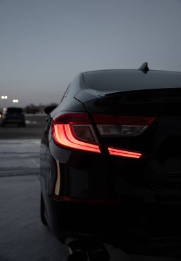 Alacakaranlıkta siyah lüks Honda Accord 'un kırmızı stop lambaları açık.