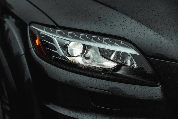水滴がついている現代の車のフロントライトのクローズアップショット — ストック写真