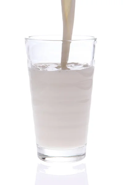 白い背景に隔離された牛乳を注ぎ込まれている牛乳のガラスの垂直閉鎖 — ストック写真