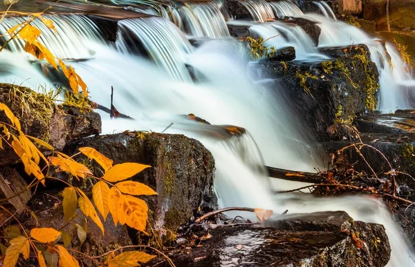 紅葉が美しい苔むした岩の上に滝の滝が長く露出している — ストック写真