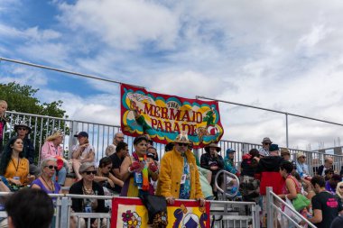 Coney Adası 'ndaki 40. Geleneksel Denizkızı Geçidi' nde bir grup insanın üzerine asılı bir poster.