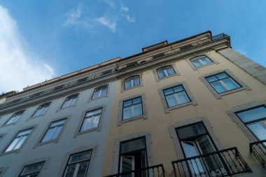 Mavi bulutlu gökyüzüne karşı eski tarz sarı bir binanın alçak açılı görüntüsü.