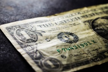 Siyah yüzeye buruşmuş bir dolarlık banknotun yakın plan çekimi.