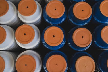 Depoda mavi ve beyaz boyanmış kil çömlek manzarası var.