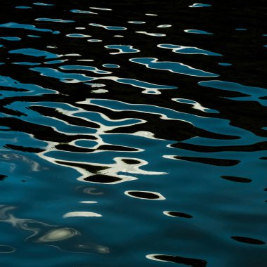 Dalgalı suya yakın çekim. Üzerinde ay yollarının yansıması var. Uzayı kopyala.