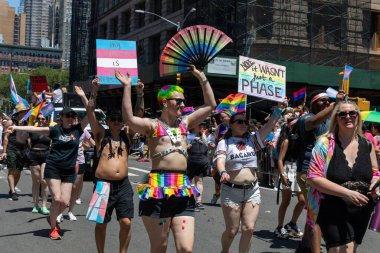 LGBT bayrakları ve geçit törenindeki gösteri işaretleriyle dolu bir kalabalık.