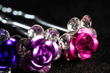 Siyah arka planda güllerle dolu renkli saç tokalarının yakın çekimi.