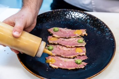 Siyah tabakta biftekli bir yemeğin yakın çekimi.