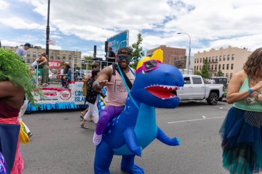 Coney Adası 'ndaki 40. Geleneksel Denizkızı Yürüyüşü sırasında şişme dinozor üzerinde bir Afro-Amerikalı.