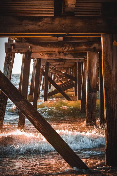 Вертикальный кадр деревянного пирса в море с брызгами воды
