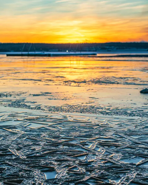 Eine Vertikale Aufnahme Eines Winteruntergangs Vom Ufer Eines Zugefrorenen Sees — Stockfoto