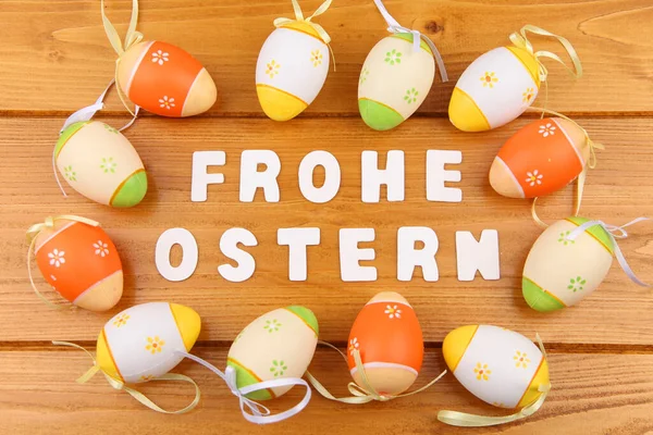 Üzerinde Mutlu Paskalyalar yazan bir tabela. Ahşap bir arka planda boyanmış yumurtalar.