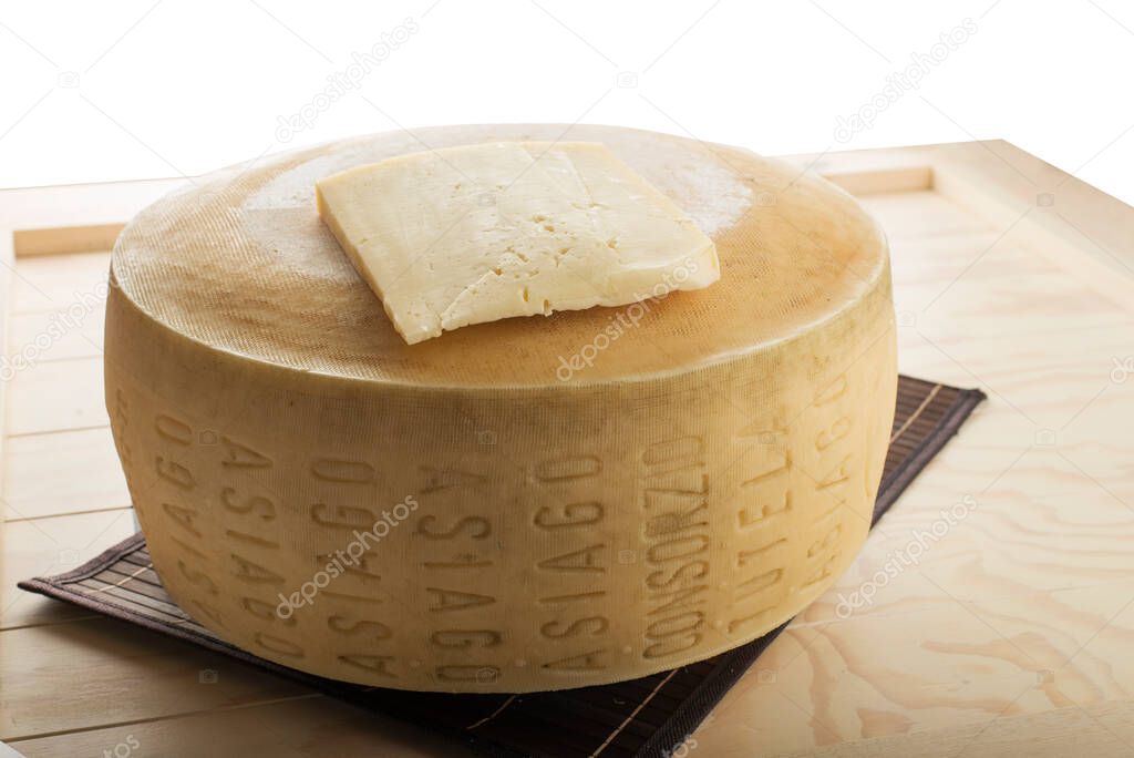 A close-up shot of an Asiago cheese loaf on a wooden plate