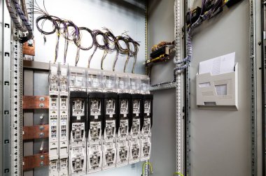 Elektrik kabloları, santral ve sigortalar duvarda asılı.