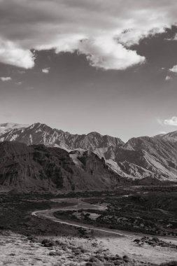Mavi gökyüzünün altında kocaman kayalar olan gri bir arazi.