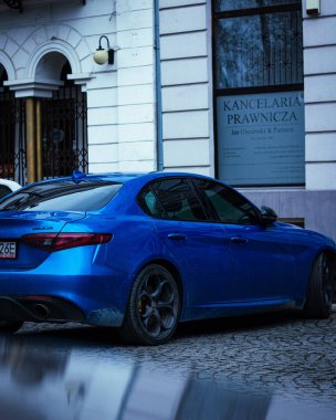 Bir binanın arka planında mavi bir Alfa Romeo Giulia Quadrifoglio.
