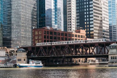 Nehirde tren köprüsü altında bir tekne ve arka planda modern binalar, Chicago City, ABD