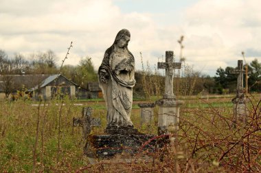 Bulutlu gökyüzünün altında mezar taşları olan eski bir mezarlık.