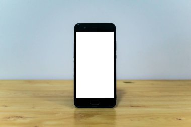 Ahşap bir masada fotokopi alanı olan boş ekranlı bir akıllı telefon.