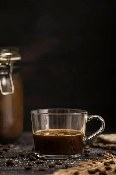 テーブルの上にコーヒー豆とガラスカップのコーヒーの垂直ショット — ストック写真