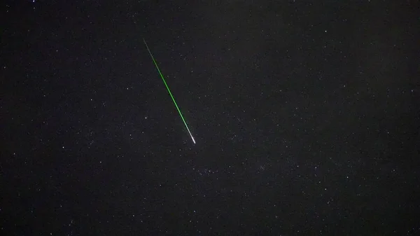 A scenic view of a shooting star in the starry sky at night