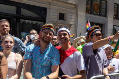 LGBT bayraklı bir kalabalık bir geçit töreninde fotoğraf çekmek için poz veriyor.