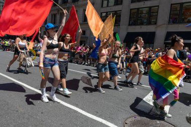 LGBT bayraklı bir kalabalık bir geçit töreninde yürüyor.