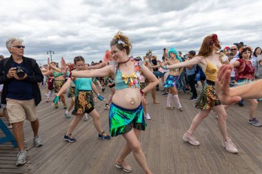 Coney Adası 'ndaki 40. Geleneksel Deniz Kızı Geçidi sırasında kalabalık içinde kostüm giymiş hamile bir kadın dans ediyor.