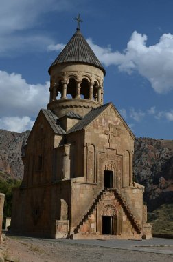 Bulutlu gökyüzünün altındaki küçük ve eski bir manastırın dikey çekimi