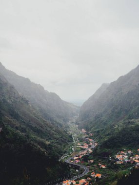 Portekiz 'in Madeira kentindeki ormanlık sisli dağlarla çevrili bir yolun dikey görüntüsü.