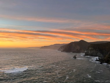 Güzel bulutlu bir gün batımı gökyüzü kayalıklarla kaplı bir deniz manzarası