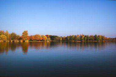 Macaristan 'ın Zalaegerszeg şehrinin arka planında sonbahar ağaçlarının oluşturduğu Gebarti Gölü.