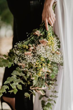 Gelinin elinde tuttuğu güzel bir düğün çiçeği buketinin dikey çekimi.