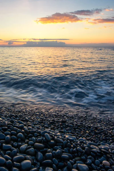 The sun rises over the famous black volcanic pebbles at Mavra Volta beach on Chios island in Greece.