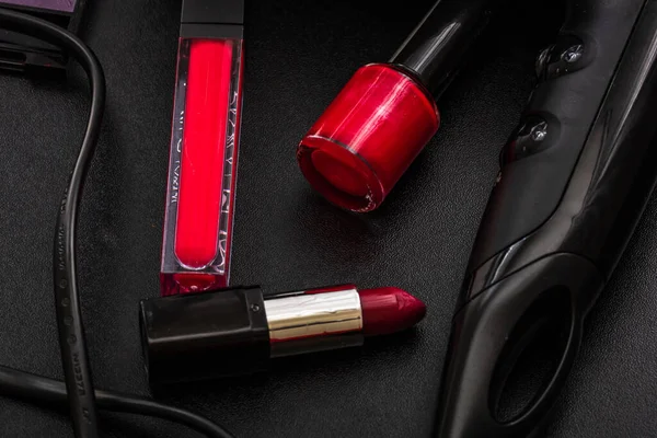 Siyah bir yüzeye kırmızı bir ruj, tırnak cilası ve üfleyici.