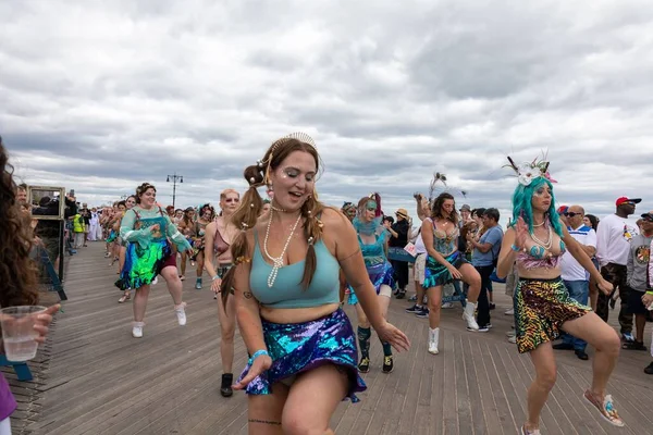 Coney Adası 'ndaki 40. Deniz Kızı Geçidi sırasında renkli kostümler içinde dans eden bir grup insan.
