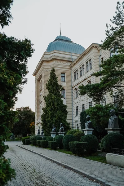 A vertical shot of a front yard of a building with a line of sculptures, Iasi, Romania