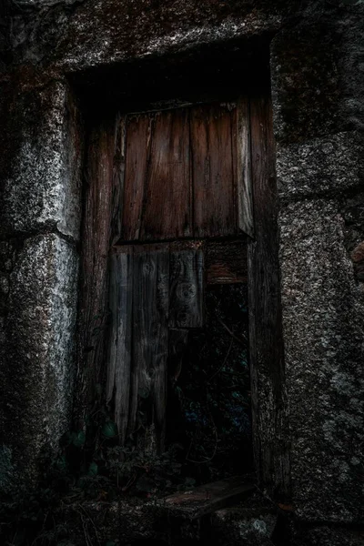 Вертикальный Снимок Ржавой Заброшенной Черной Двери Грубой Каменной Стене — стоковое фото