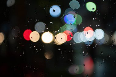 Şehirde gece penceredeki yağmur damlalarının görüntüsü, arka plan gömme, arkaplan için soyut bokeh