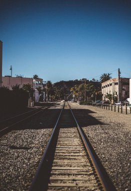 Gökyüzüne karşı binalar ve ağaçlarla çevrili bir demiryolu.