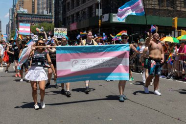 LGBT bayrakları ve geçit törenindeki gösteri işaretleriyle dolu bir kalabalık.