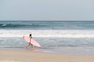 Puerto Escondido 'daki Zicatela plajında sörf tahtası tutan genç bir kız.