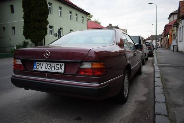 Romanya 'nın Brasov kentinde bir caddeye park edilmiş klasik koyu kırmızı bir arabanın güzel bir görüntüsü