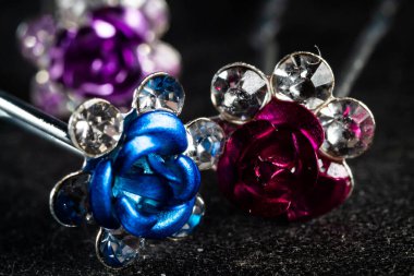 Renkli saç tokalarının yakın plan fotoğrafı. Arka planda siyah güller var.