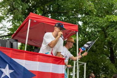 Genç bir adam mikrofonla konuşuyor ve New York 'ta Porto Riko Günü Geçidi' ni kutluyor.