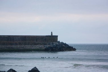 Kayalık bir uçurum manzarası ve bulutlu bir günde dalgalar.
