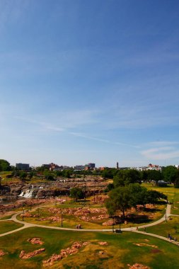 Güney Dakota 'daki Falls Park' ın arka planda şelaleler ve binalarla dikey görüntüsü.