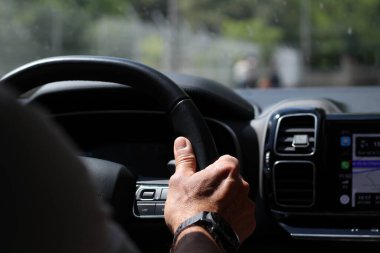 Arabasının direksiyonunda dinlenen bir adamın sağ elinin yakın çekimi ve GPS çalışıyor.