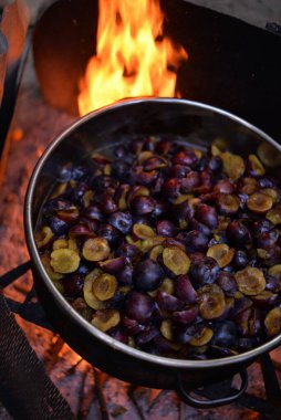 Dilimlenmiş eriklerin dikey yakın çekimi şöminenin üstünde pişiriliyor.