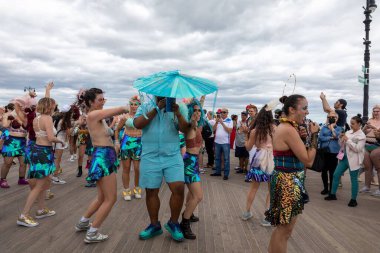 Coney Adası 'ndaki 40. Deniz Kızı Geçidi sırasında renkli kostümler içinde dans eden bir grup insan.